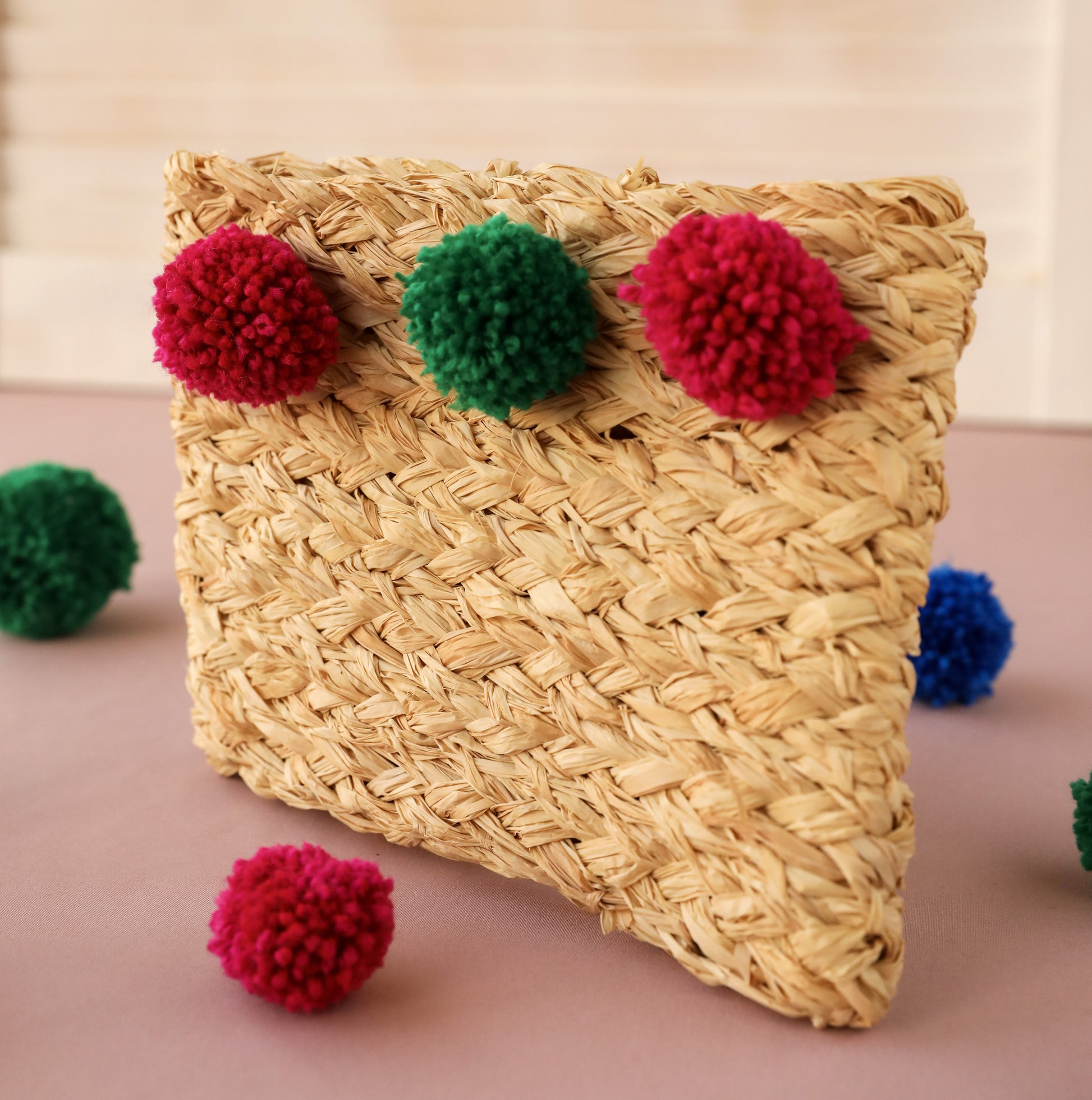 Handmade natural raffia clutch purse bag with different coloured pom pom decoration, created using a complete beginners raffia course