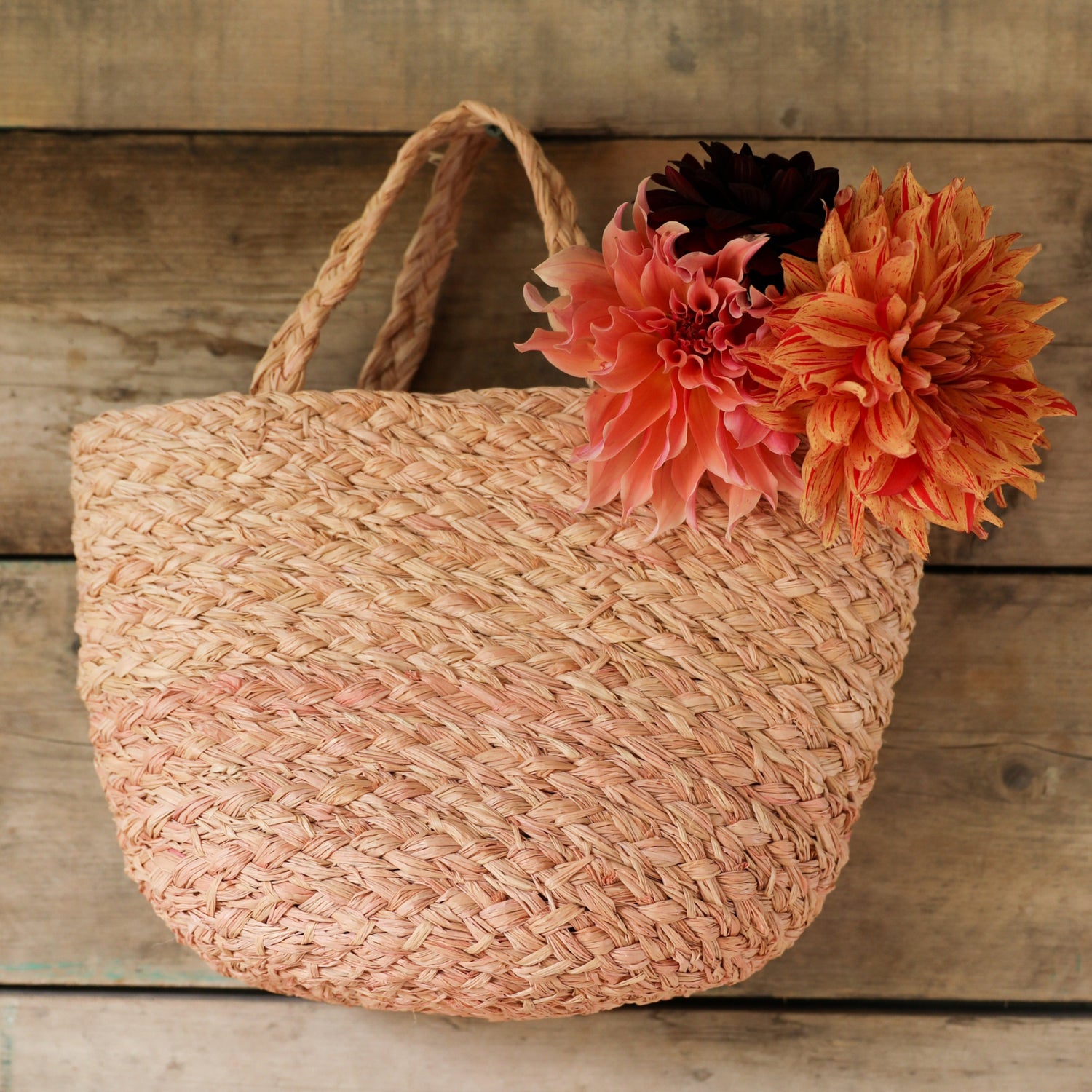 Raffia woven  bag with flowers on a wooden surface