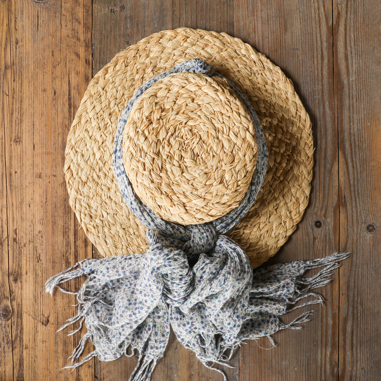 Handmade natural raffia sunhat with scarf decoration on wood background
