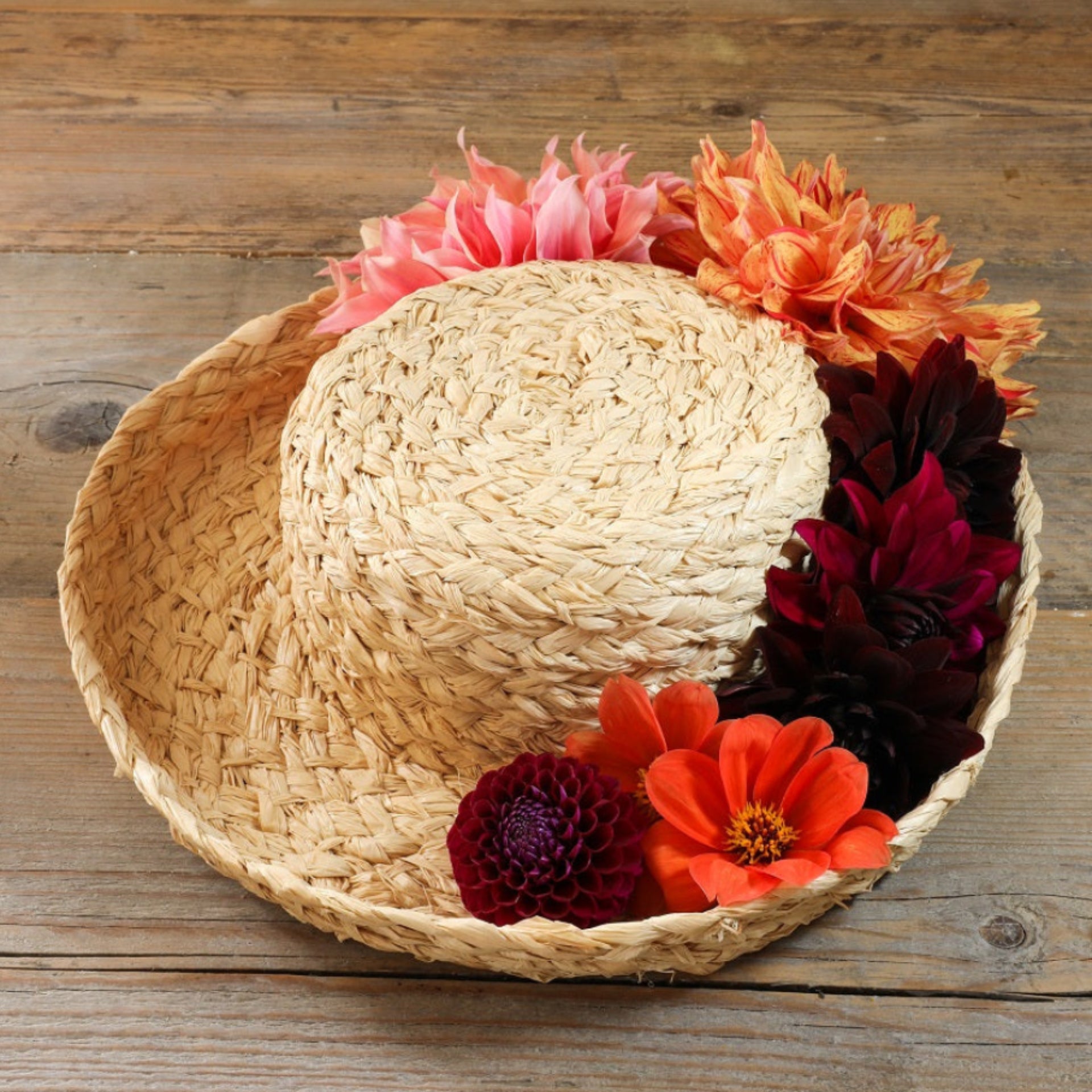 Natural handmade raffia breton hat with brim up and flowers in the brim wooden background