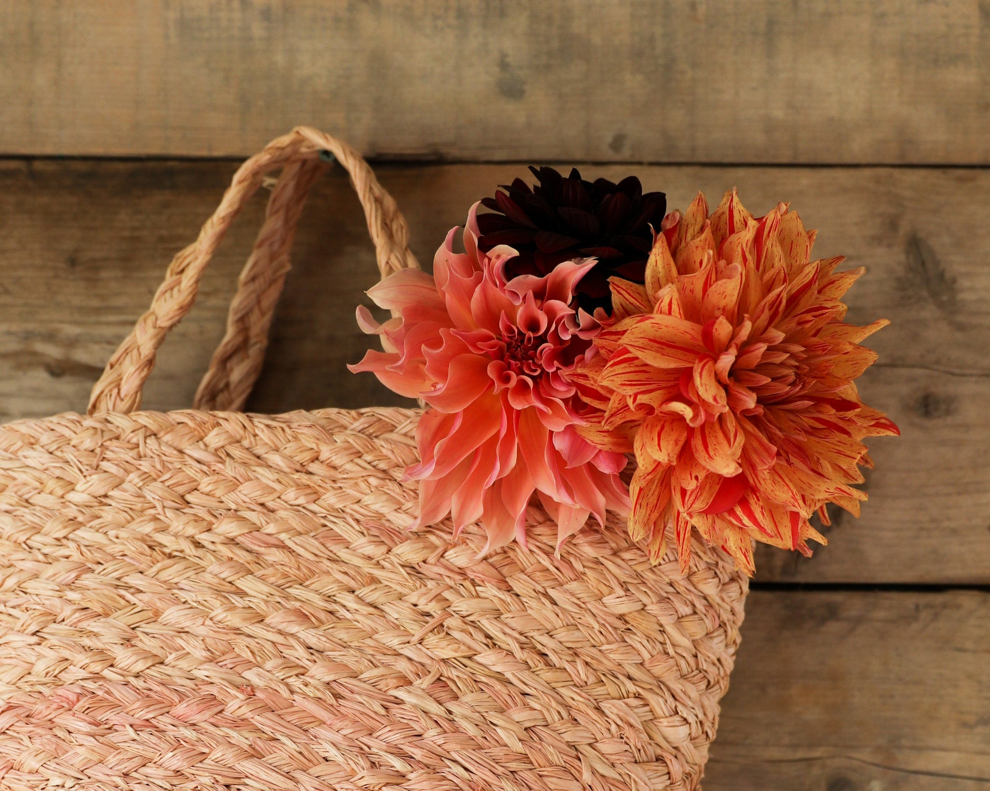 Raffia woven basket with three bright flowers from the top of it