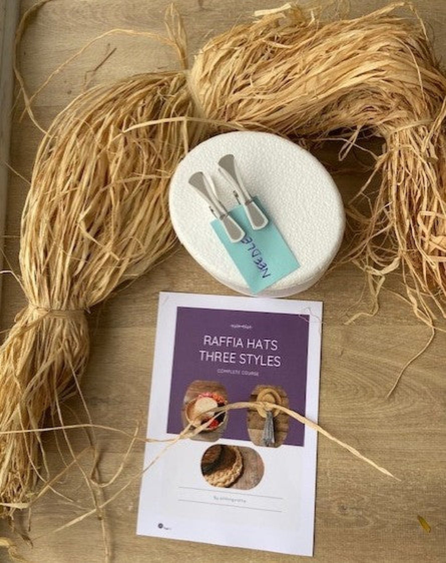 Natural raffia with hat block and printed course instructions with a wood background